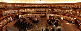 Panoramic view of a grand circular library with shelves full of books and study desks.